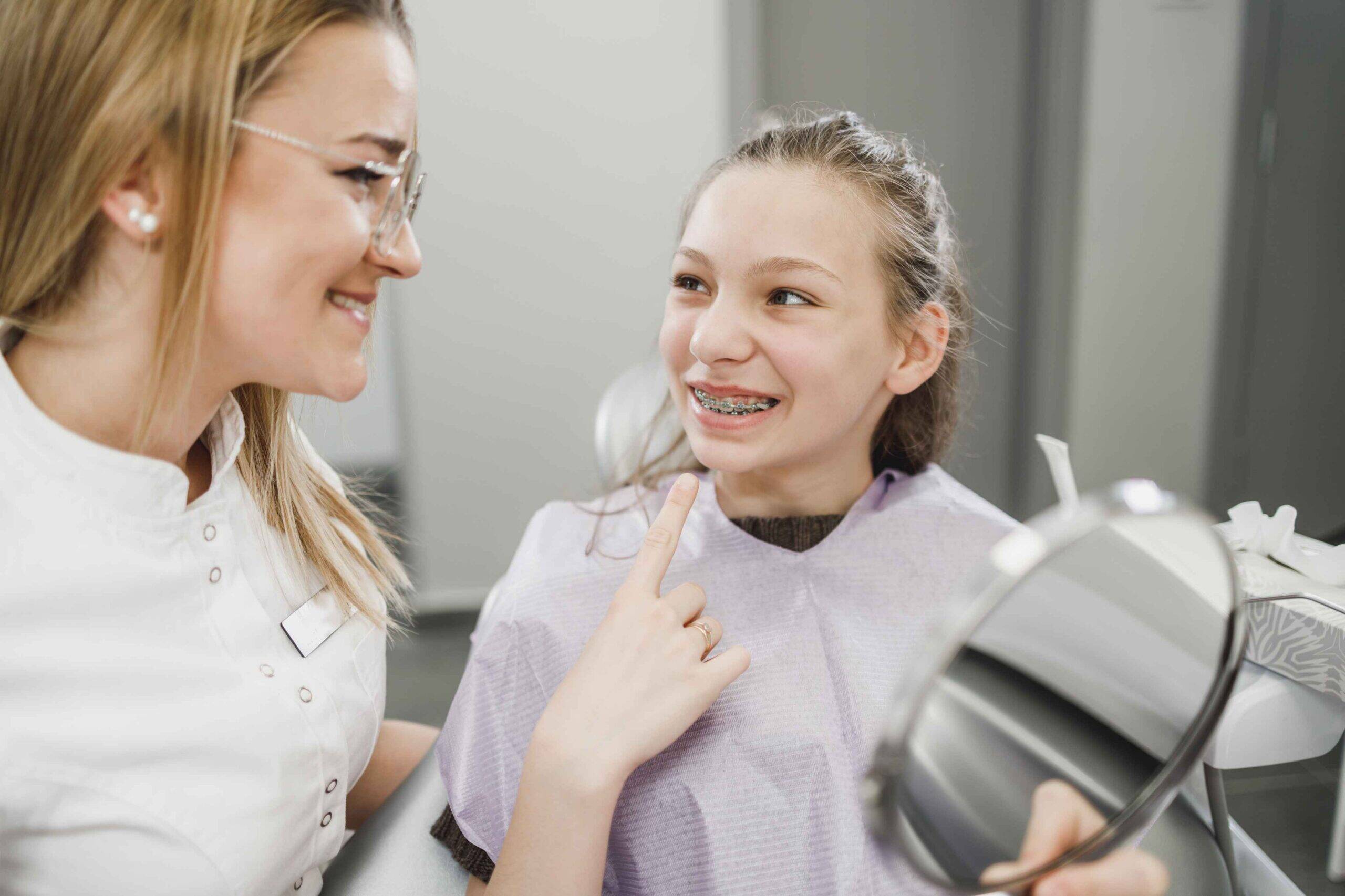 Orthodontist showing braces to a smiling child patient.